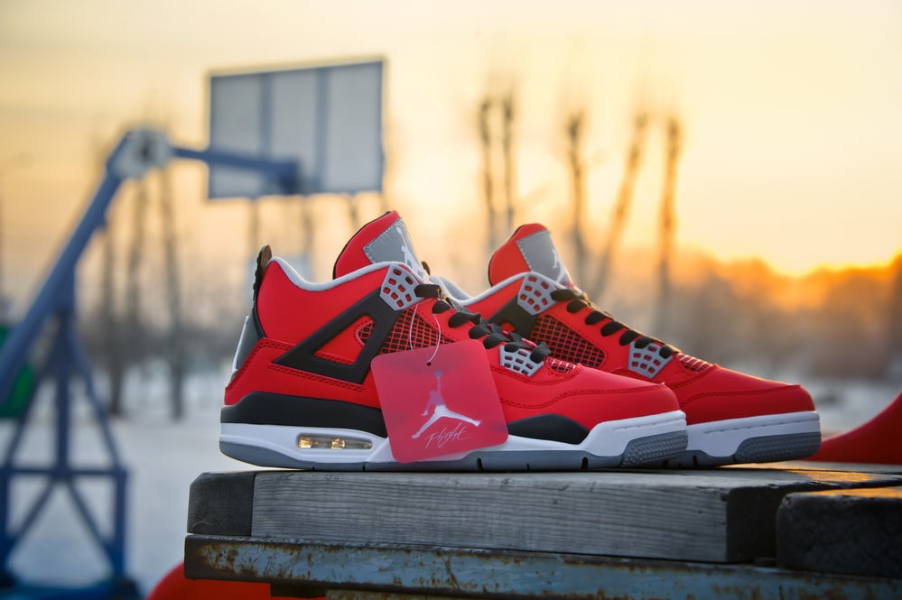 Nike Air Jordan IV Retro basketball shoes in fire red, cement grey and black colors shot outdoors at the basketball court background. Krasnoyarsk, Russia - February 7, 2015